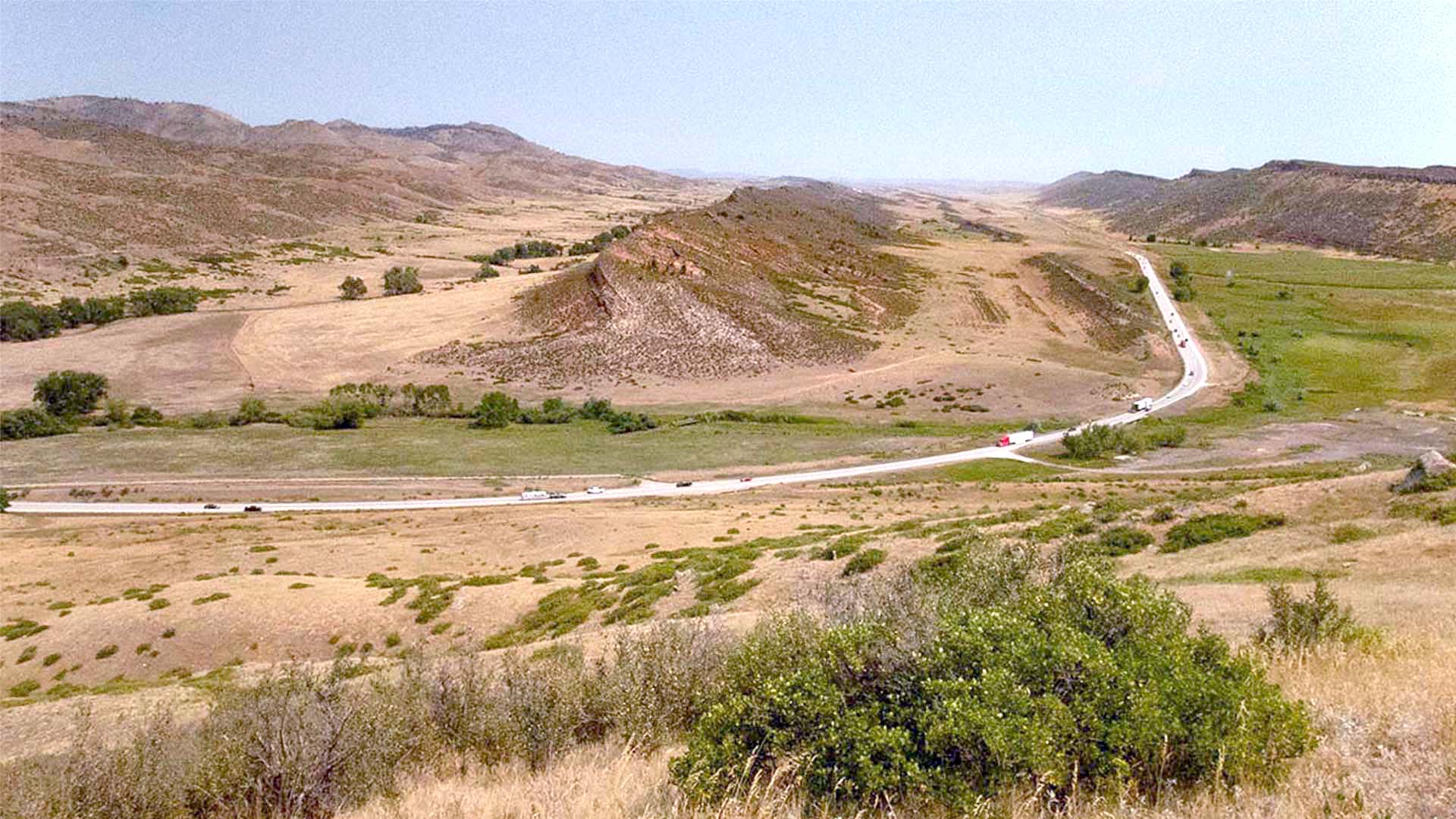 Road going through a valley with hills surrounding.