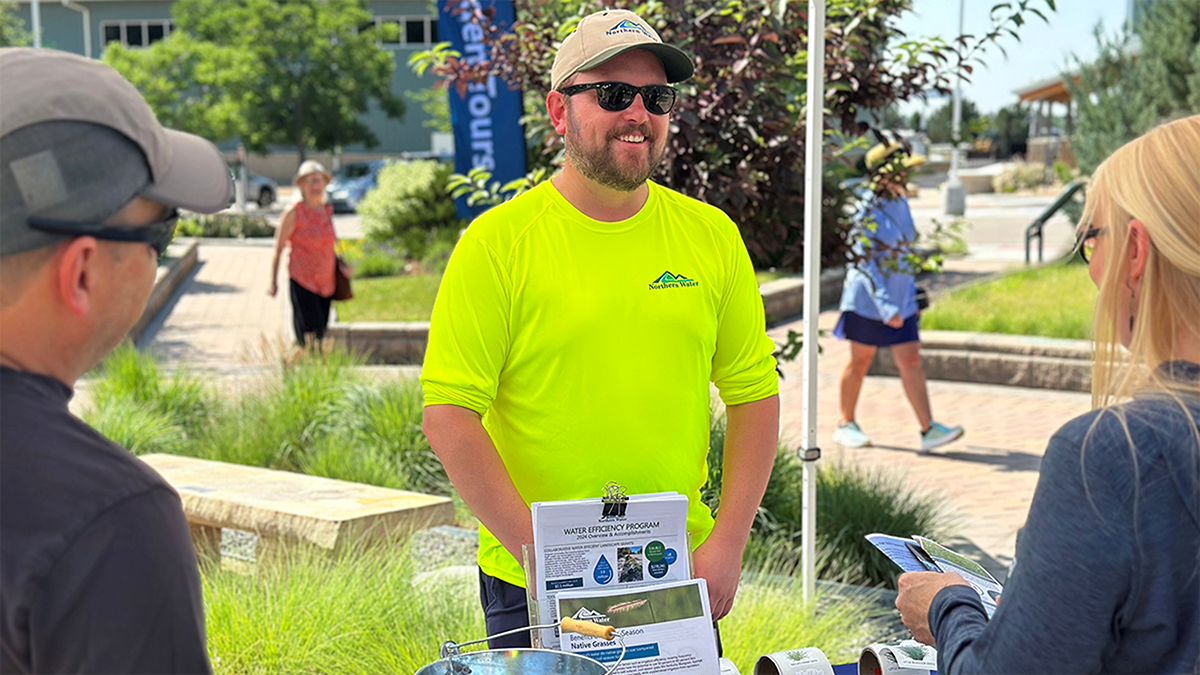 A man talking to people at the Gardens Fair. 