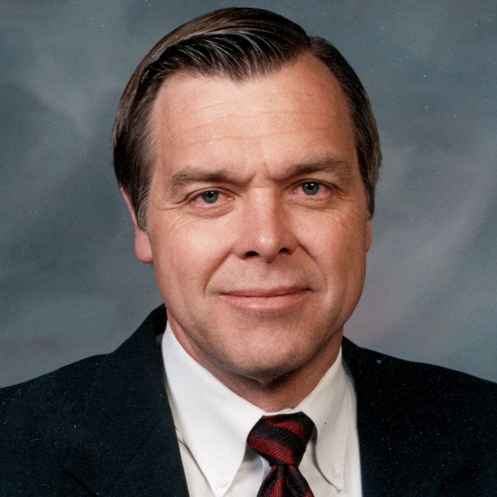 Man in a black suit with white shirt and a striped tie.