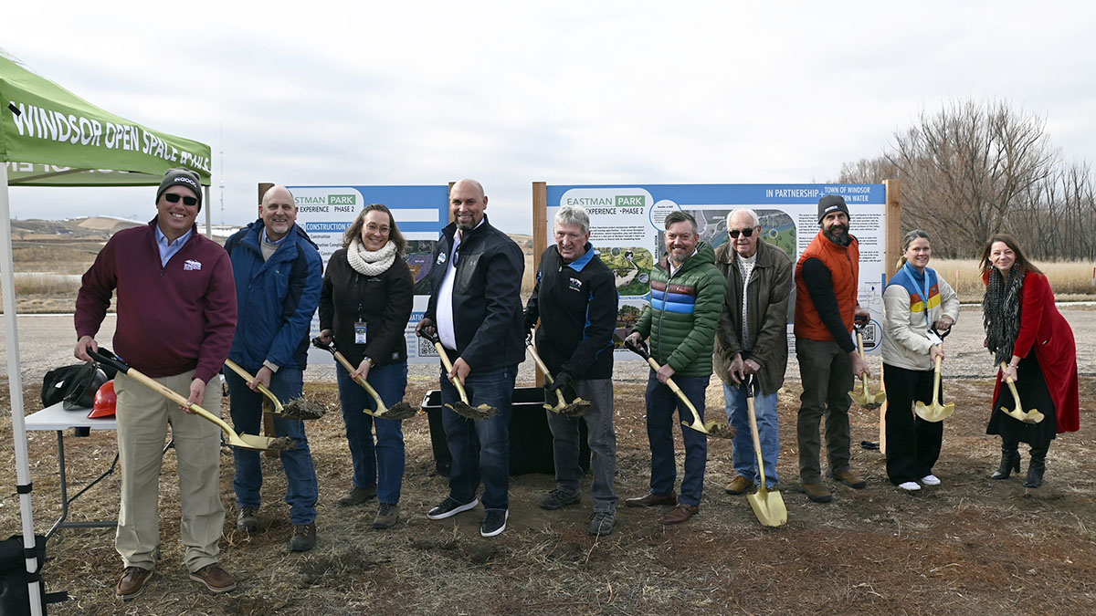 People lined up holding shovels of dirt at a groundbreaking.
