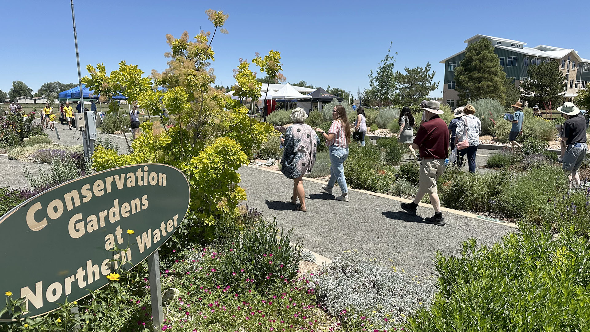 People walking by the sign in the Conservation Gardens.