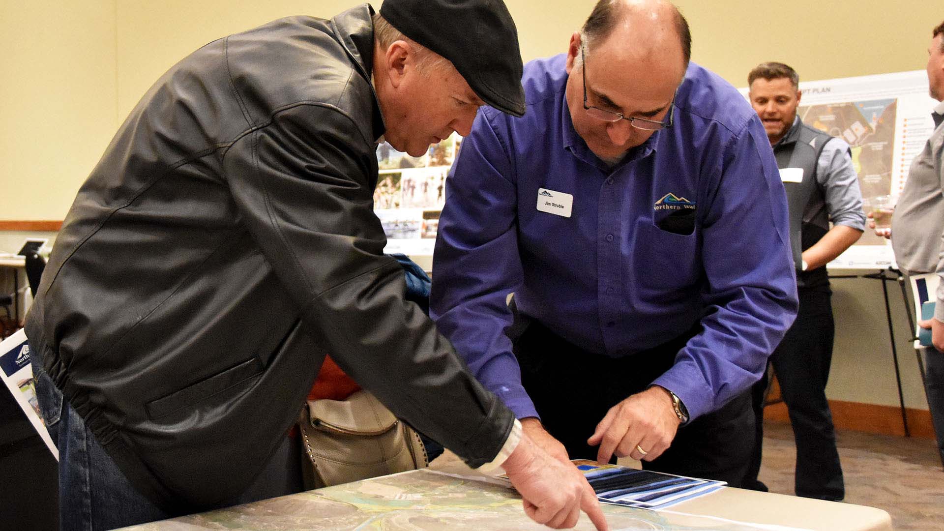 Two men pointing at items on a map.