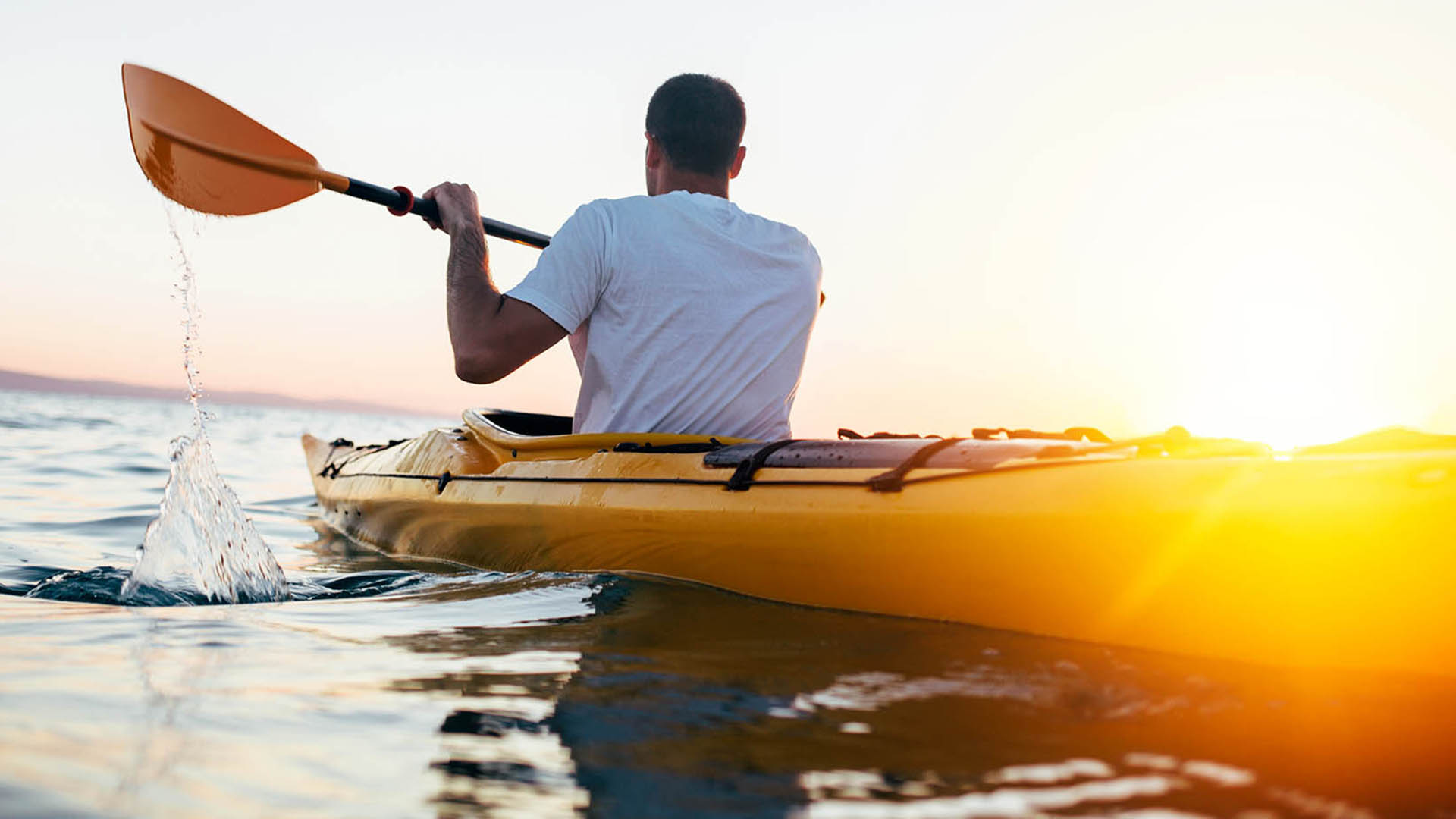 Man kayaking during sunset on a lake.