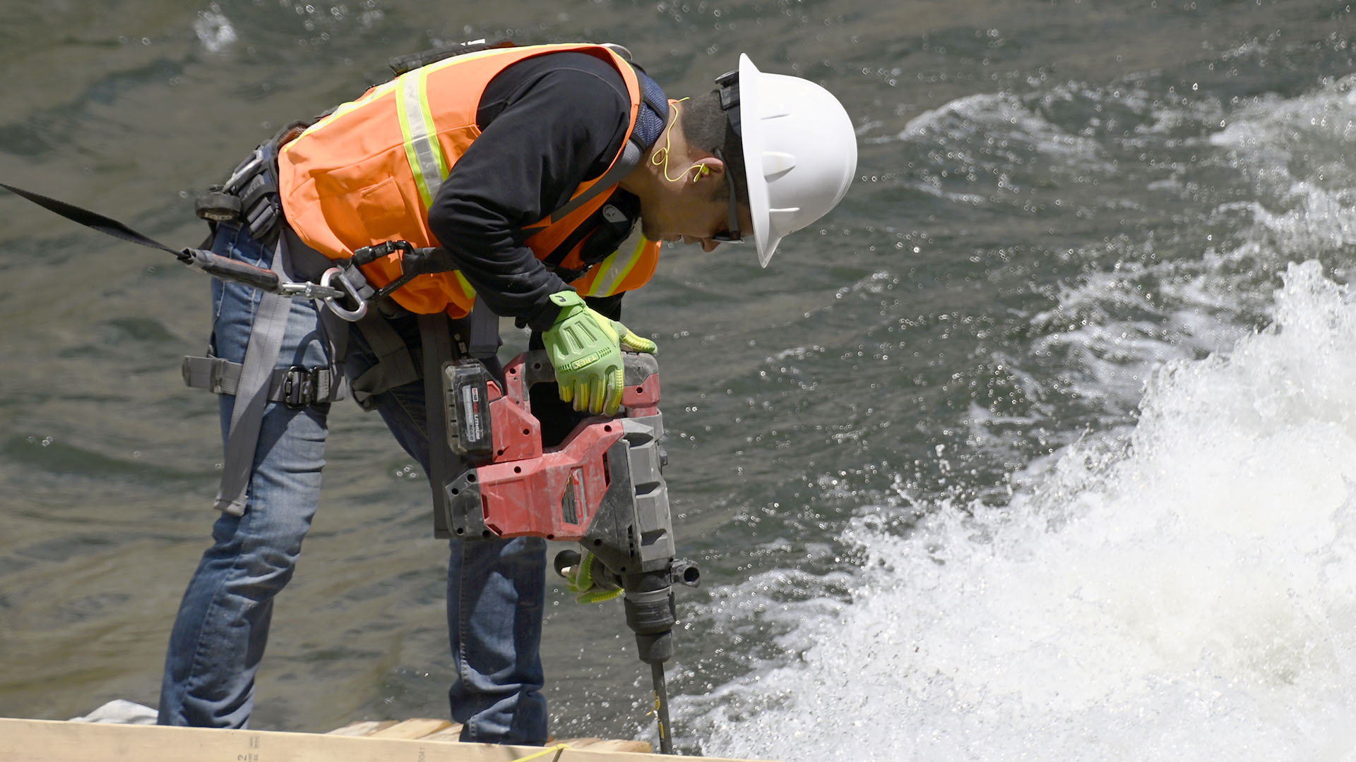 A man chiseling concrete with water flowing around him.