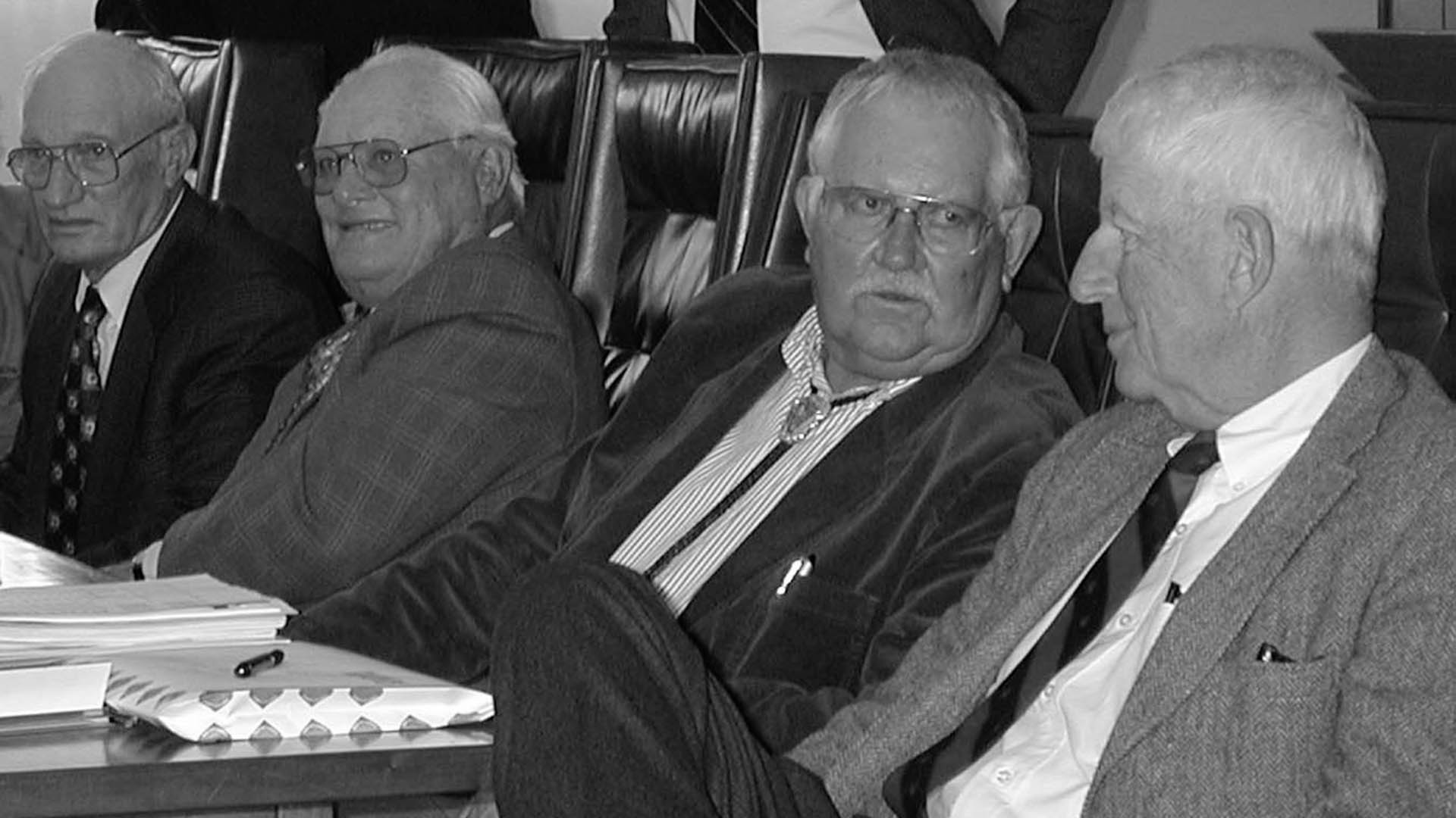 Four past Board members sitting in chairs. 