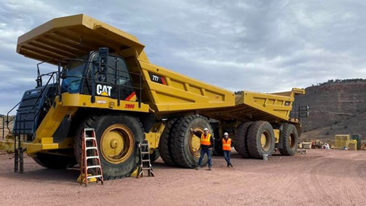 Man and woman standing next to a 100-ton, 777-haul truck.