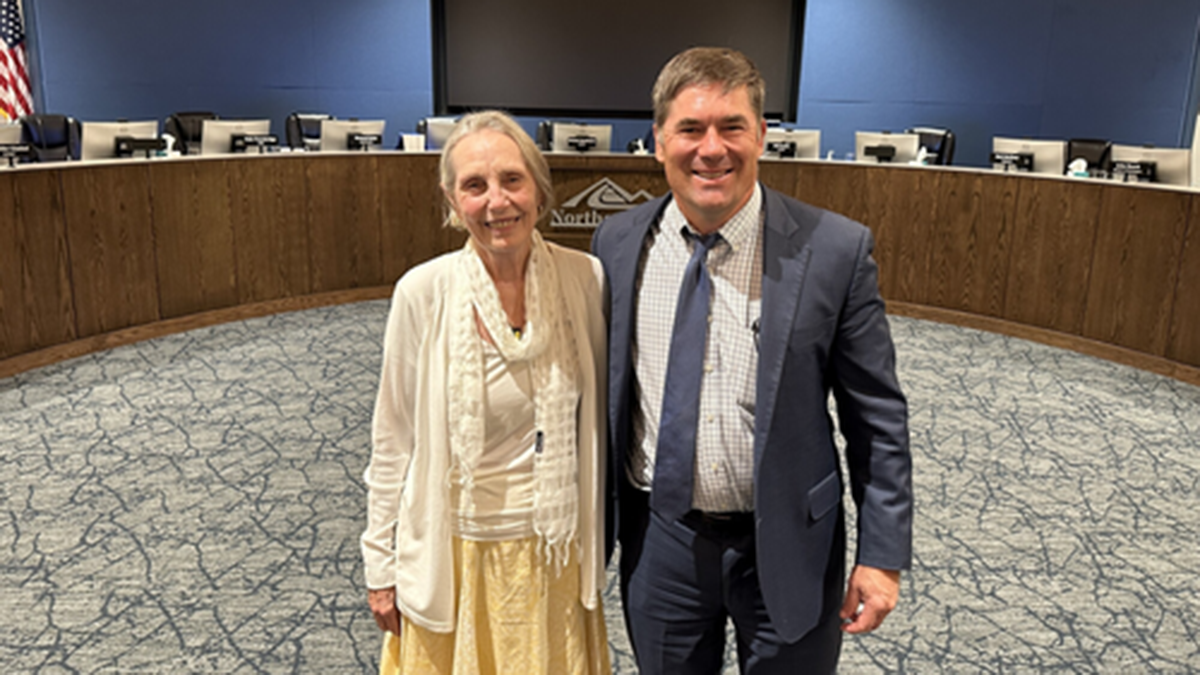 Two people standing and smiling with dais in the background