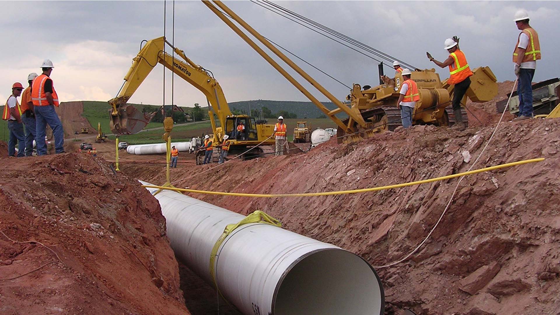 Men surveying the pipe lifted into place for the Pleasant Valley Pipeline.