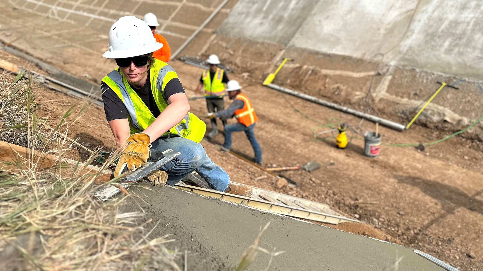Woman in hardhat smoothing out concrete.