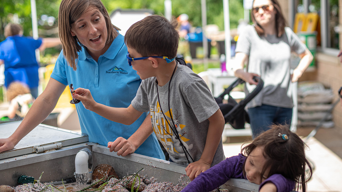Kids at an activity table with an adult engaging with them.