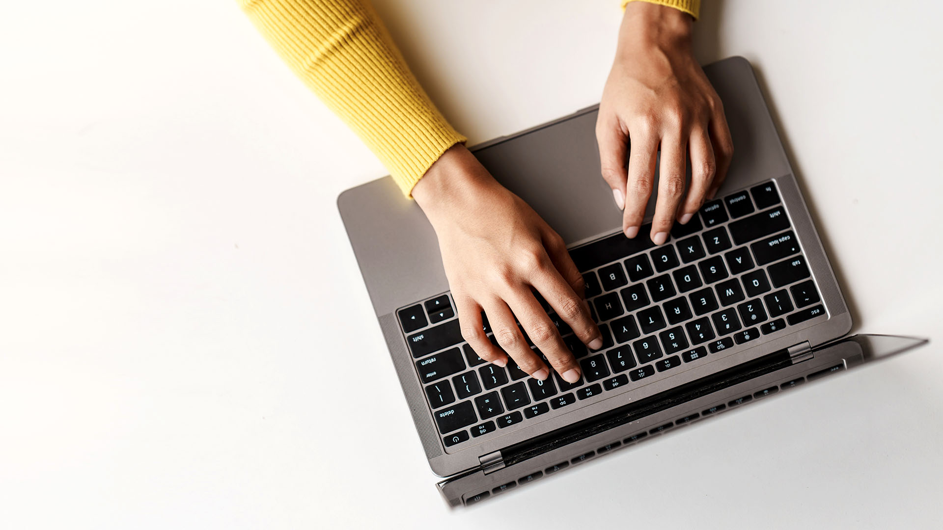 Women in yellow shirt typing on a computer.