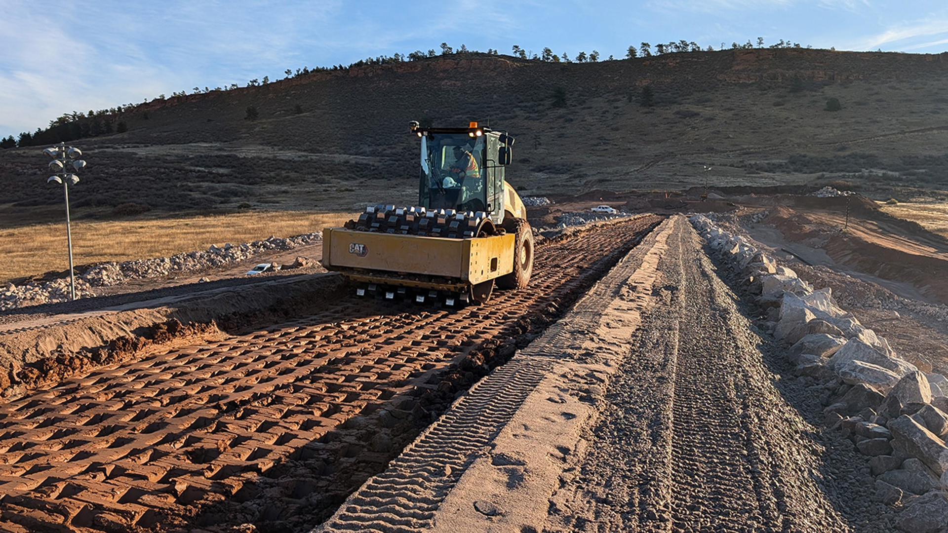 A machine rolling over clay installed for a dam.