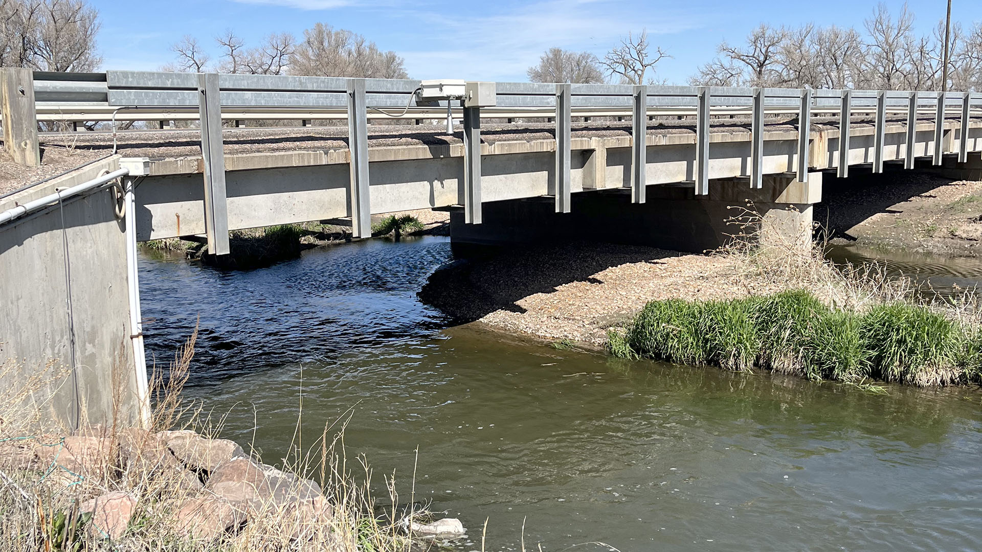 A river flowing underneath a bridge. 