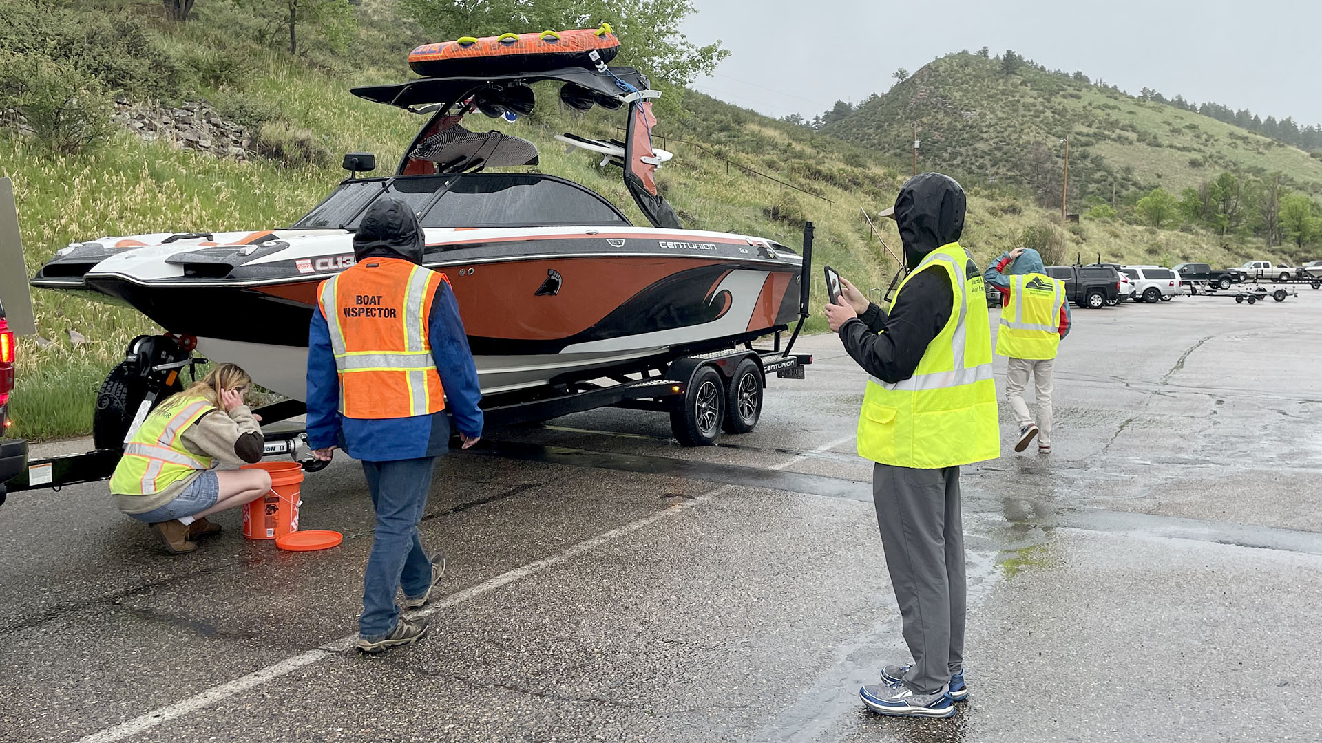 Four people in vests inspecting a boat on a trailer for aquatic nuisance species. 