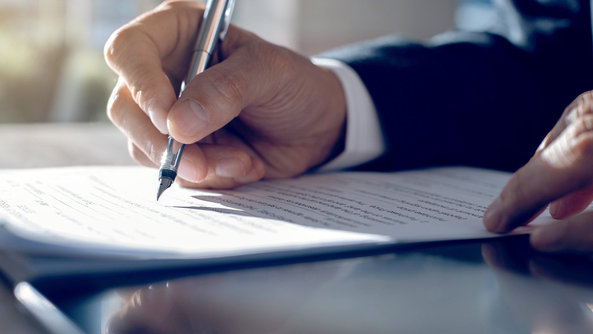 Hand holding a pen and signing a contract piece of paper. 