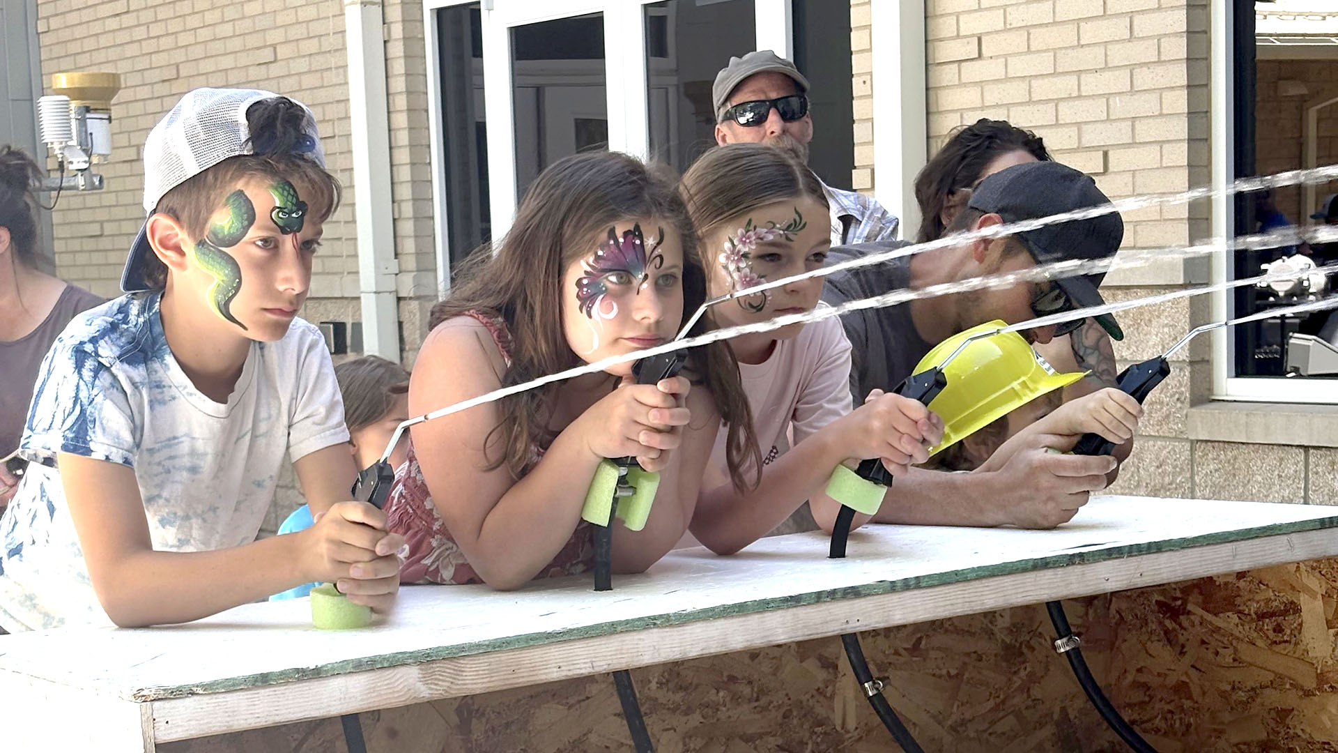 Teenagers with faces painted shooting water guns.