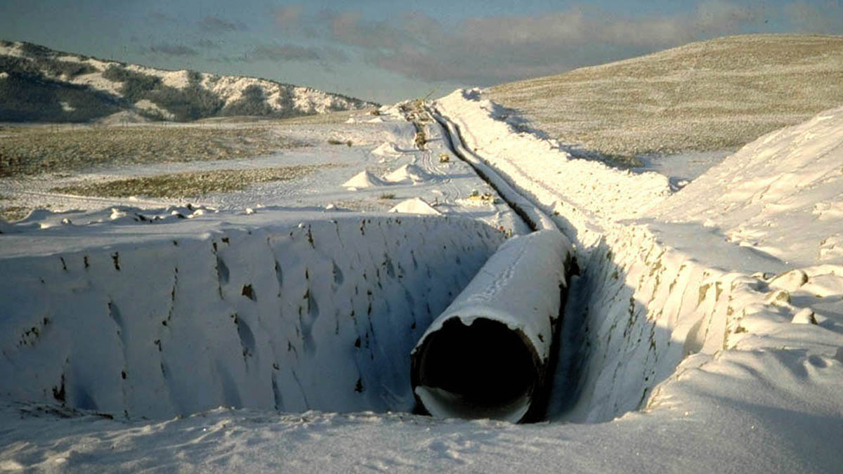 Large in-ground pipe in snow-covered ditch as part of a construction project.