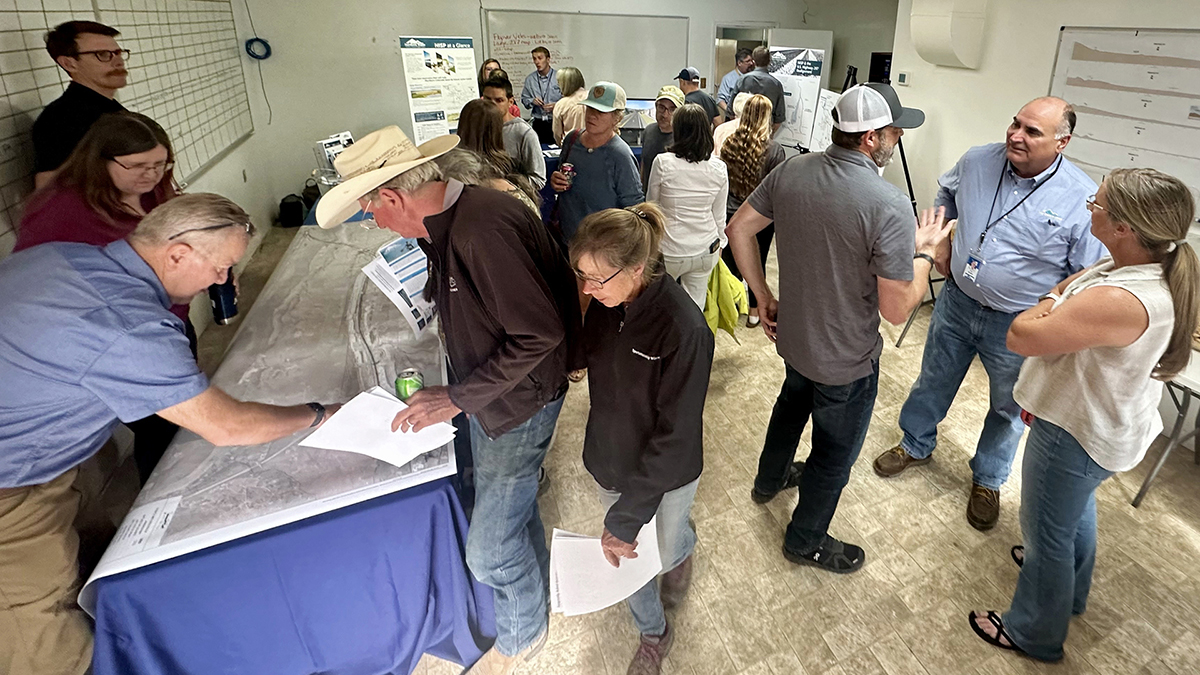 People gather in a room, talking to each other and looking at information at the NISP open house.