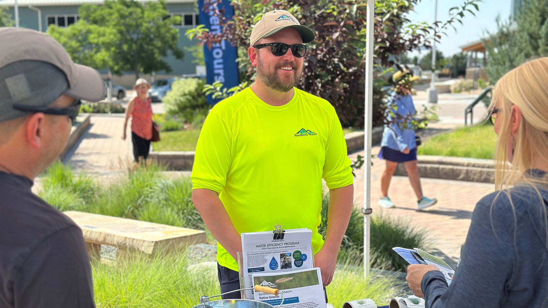 Man in bright yellow shirt talking to fair attendees. 