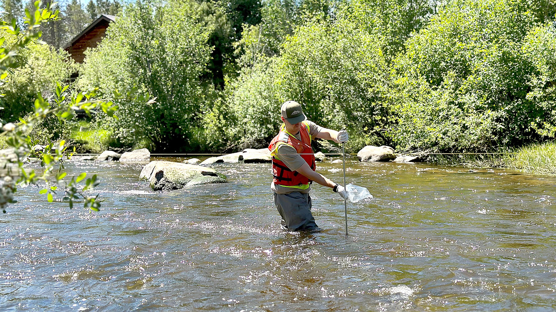 Man standing in river measuring flow data.
