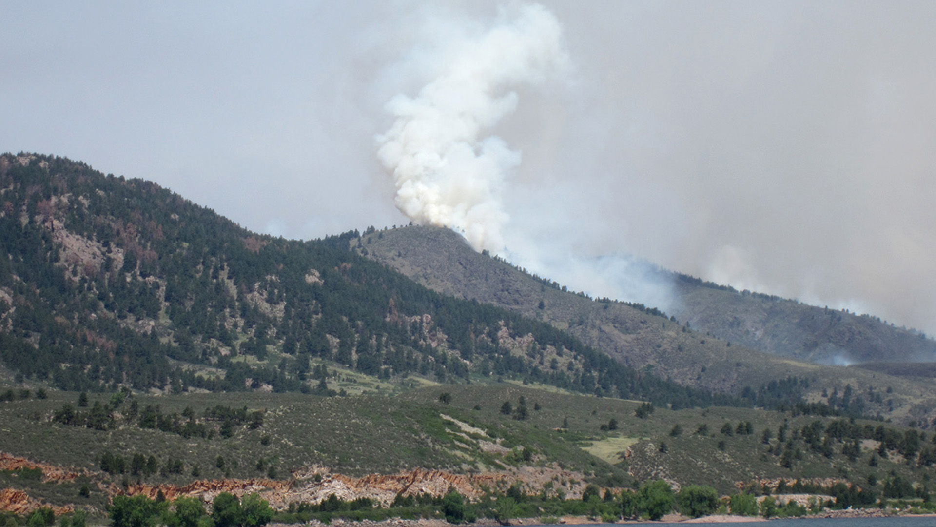 Plumes of smoke rising from the foothills from a fire.