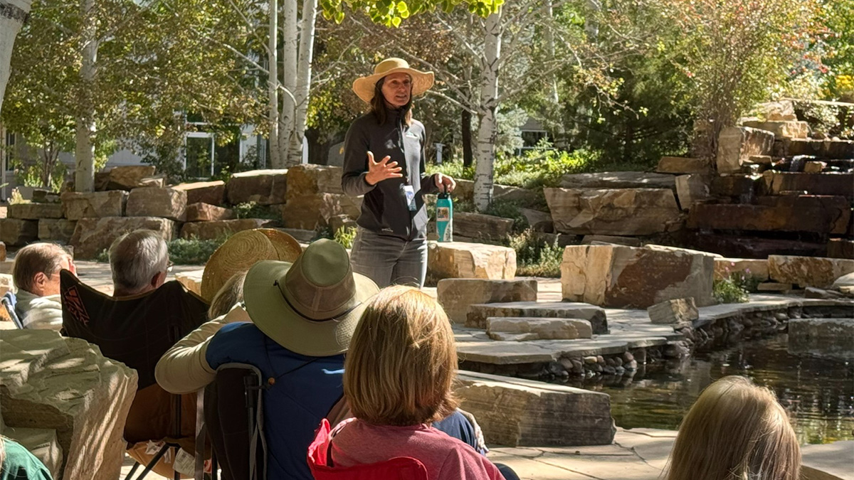 Woman giving a presentation outdoors to a group of people.