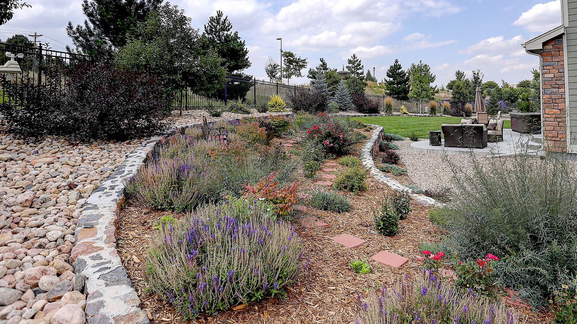 Example of a xeriscape yard with water-wise plants, rock, boulders and trees.