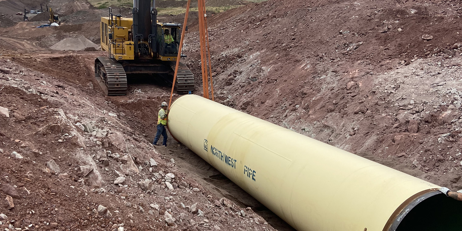 Man guiding in a piece of pipe for the Chimney Hollow Conduit.