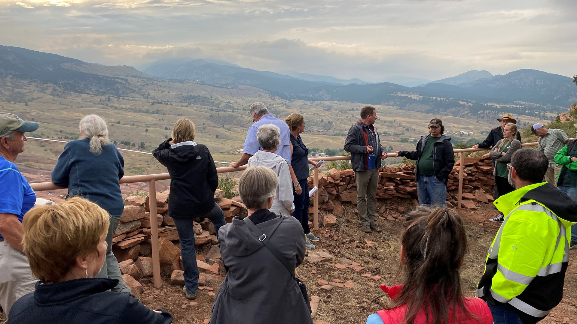 A tour group looks at the site from an overlook location east of the construction site.