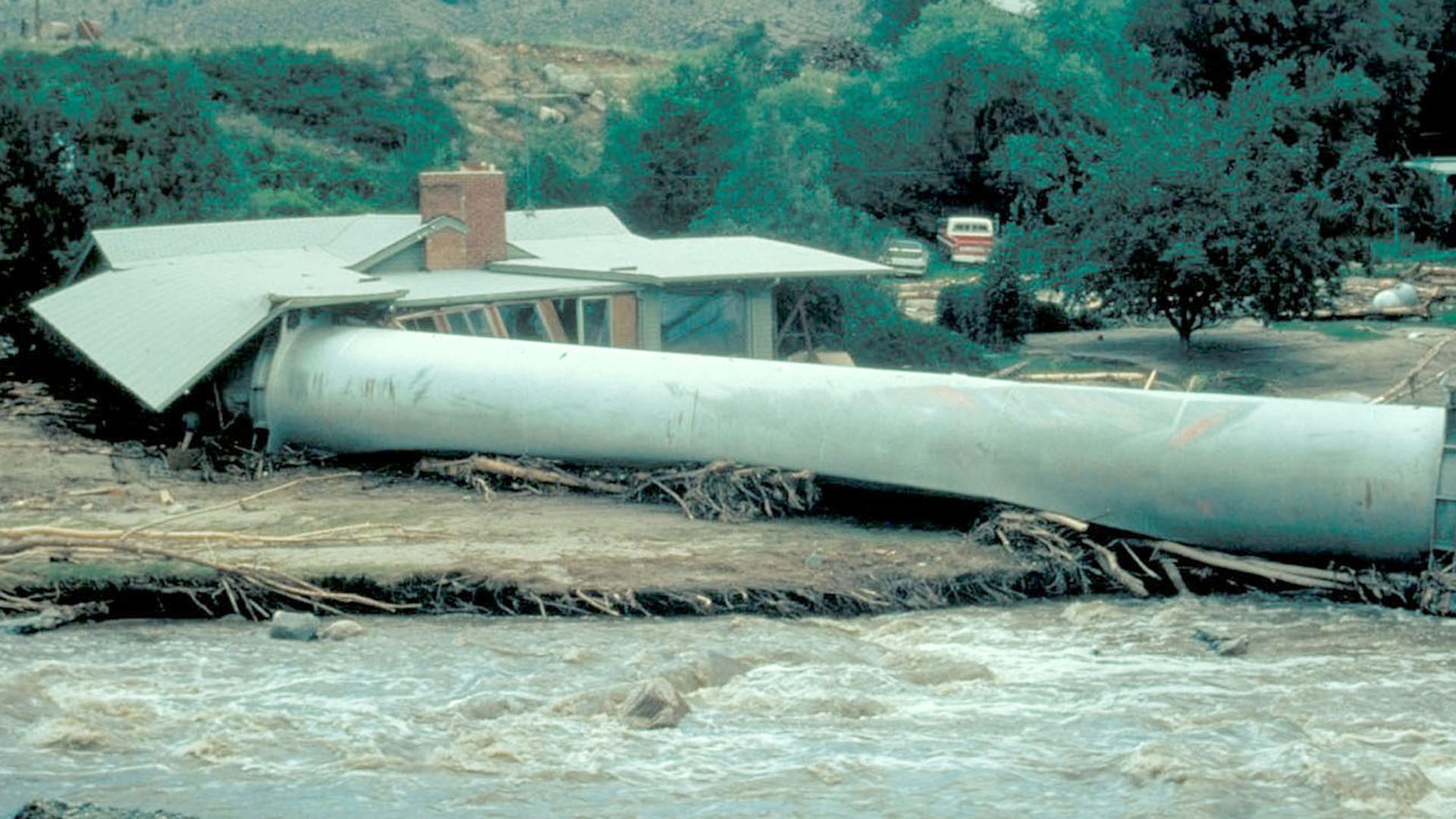 A large water pipe that got washed down river from a flood into a house.