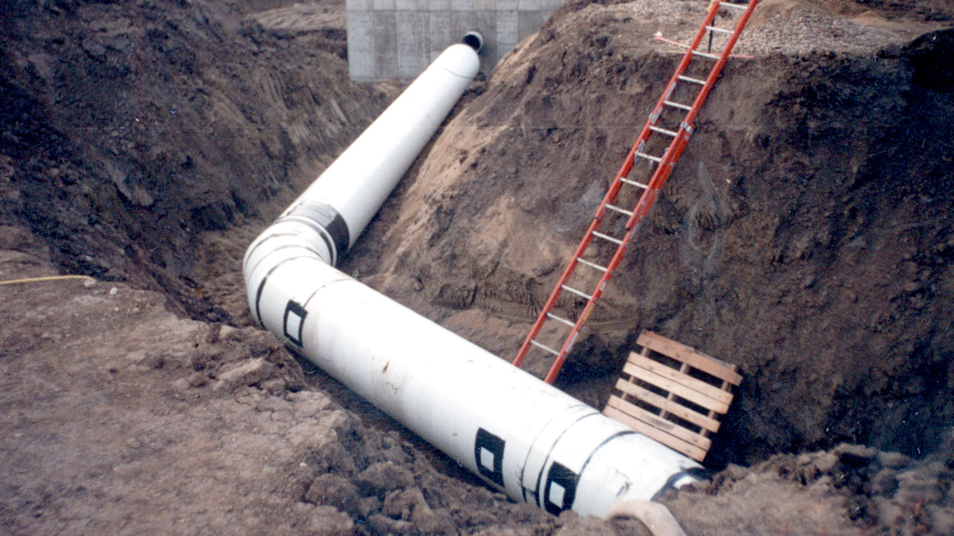 A ladder leading down to pipe laid in the ground.