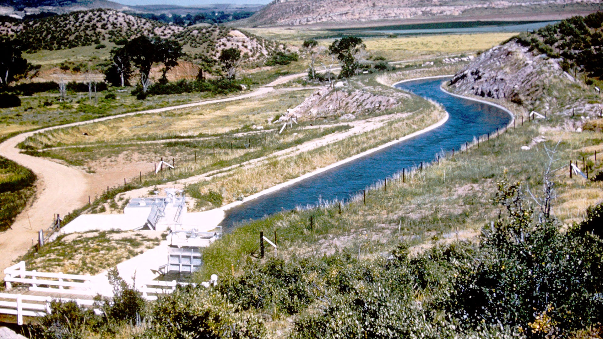 Water flowing down a canal with foothills surrounding.