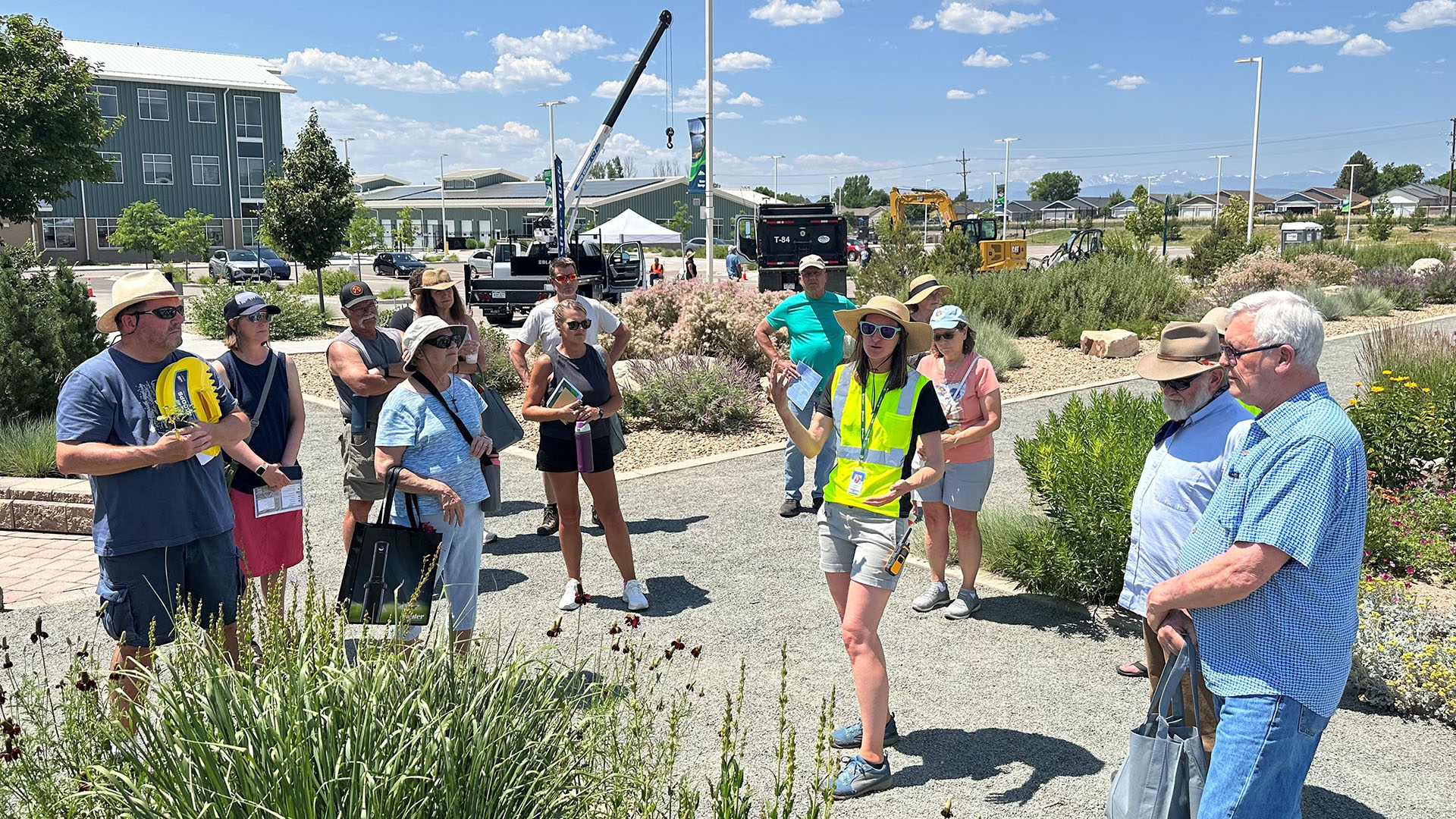 Lady giving a gardens tour surrounded by attendees at an event. 