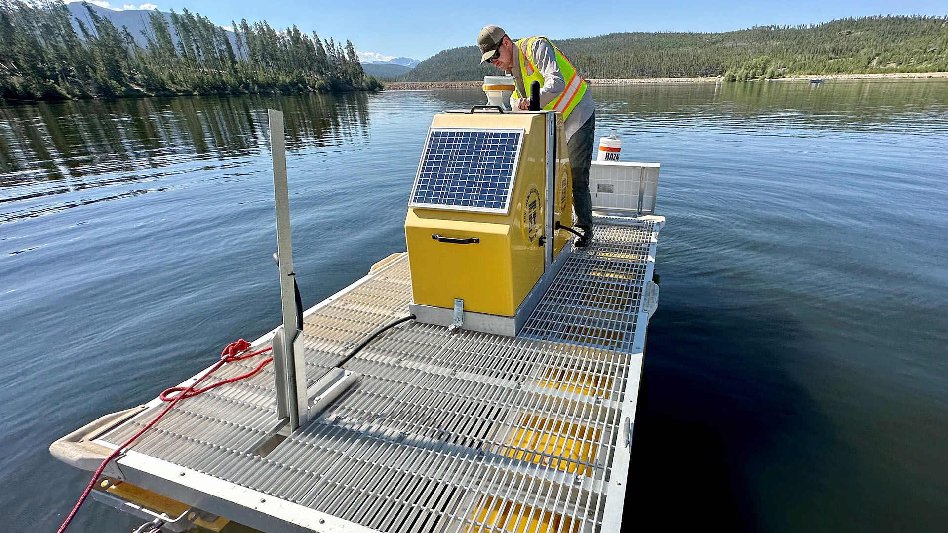 Man standing on a buoy in the middle of a lake, which is used for water quality.