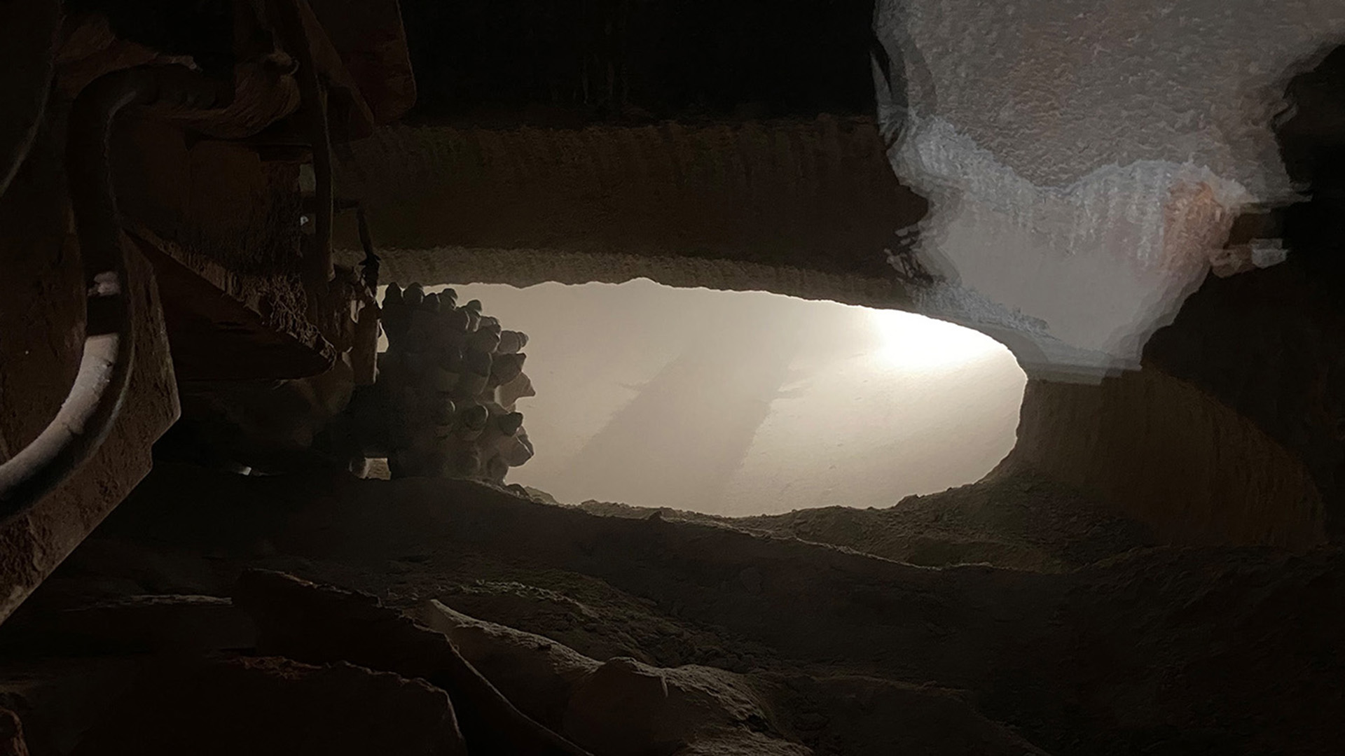 A machine cuts through rock to tunnel through a hole.