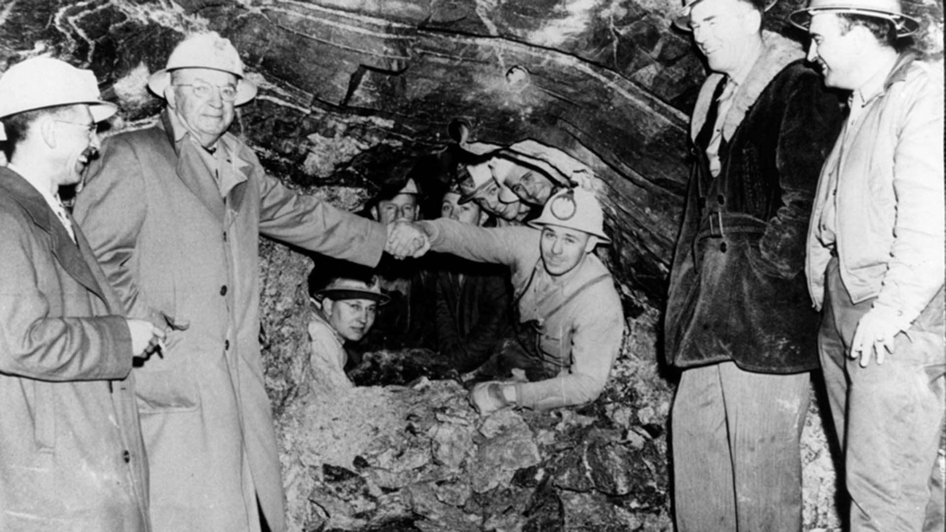 Men shaking hands inside the construction of the Adams Tunnel.