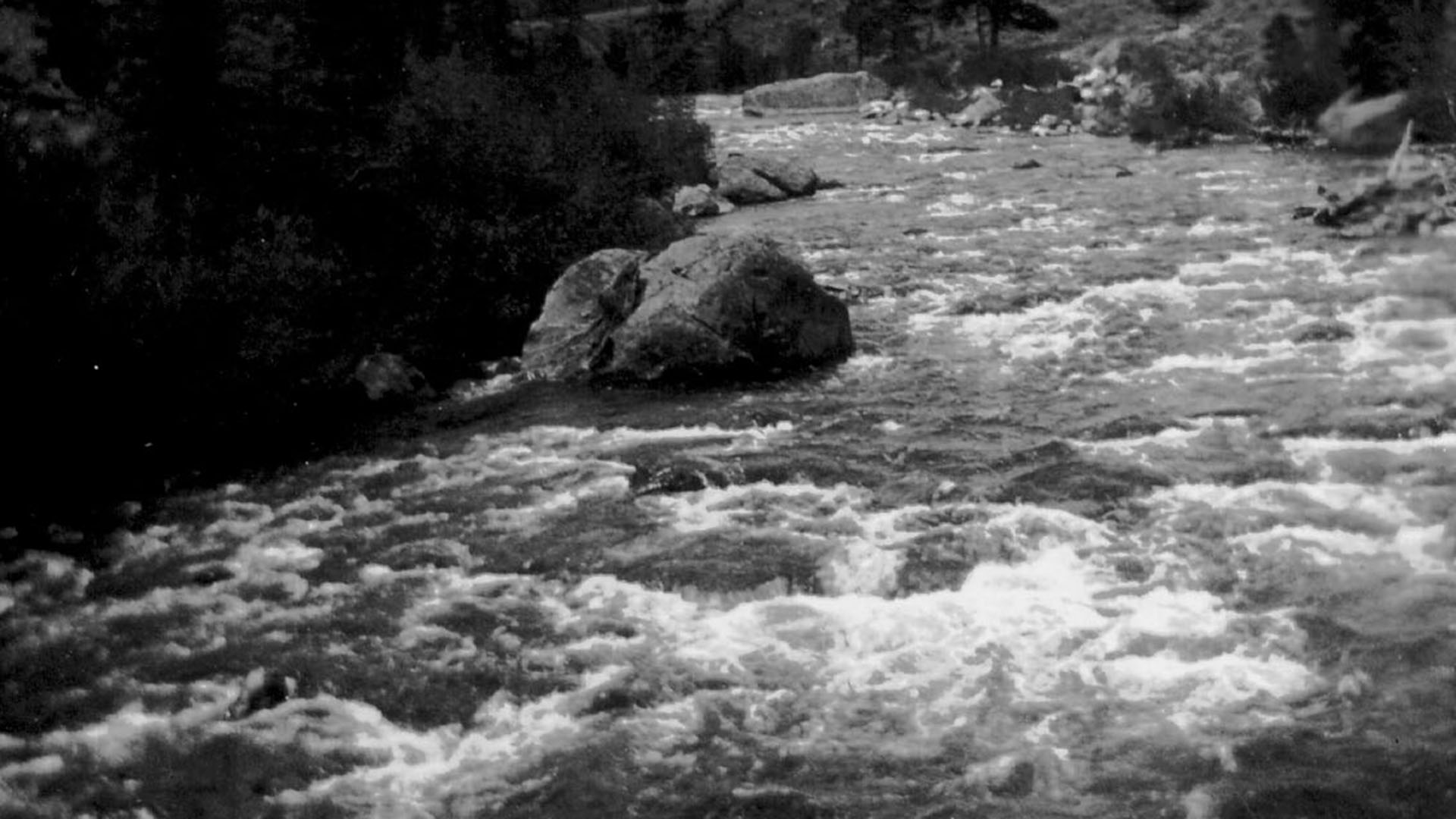 Historic image of water rolling over rocks in river.