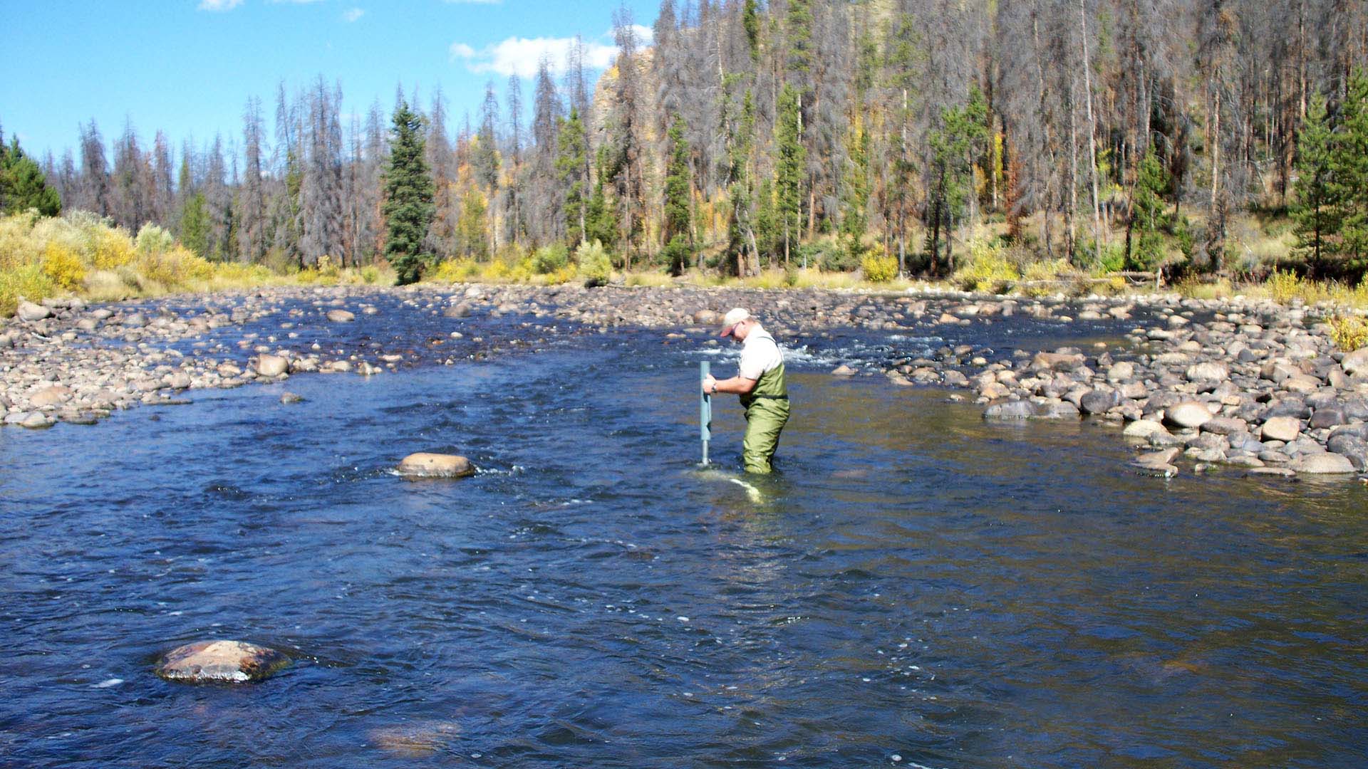 Man standing in river collecting temperature data.