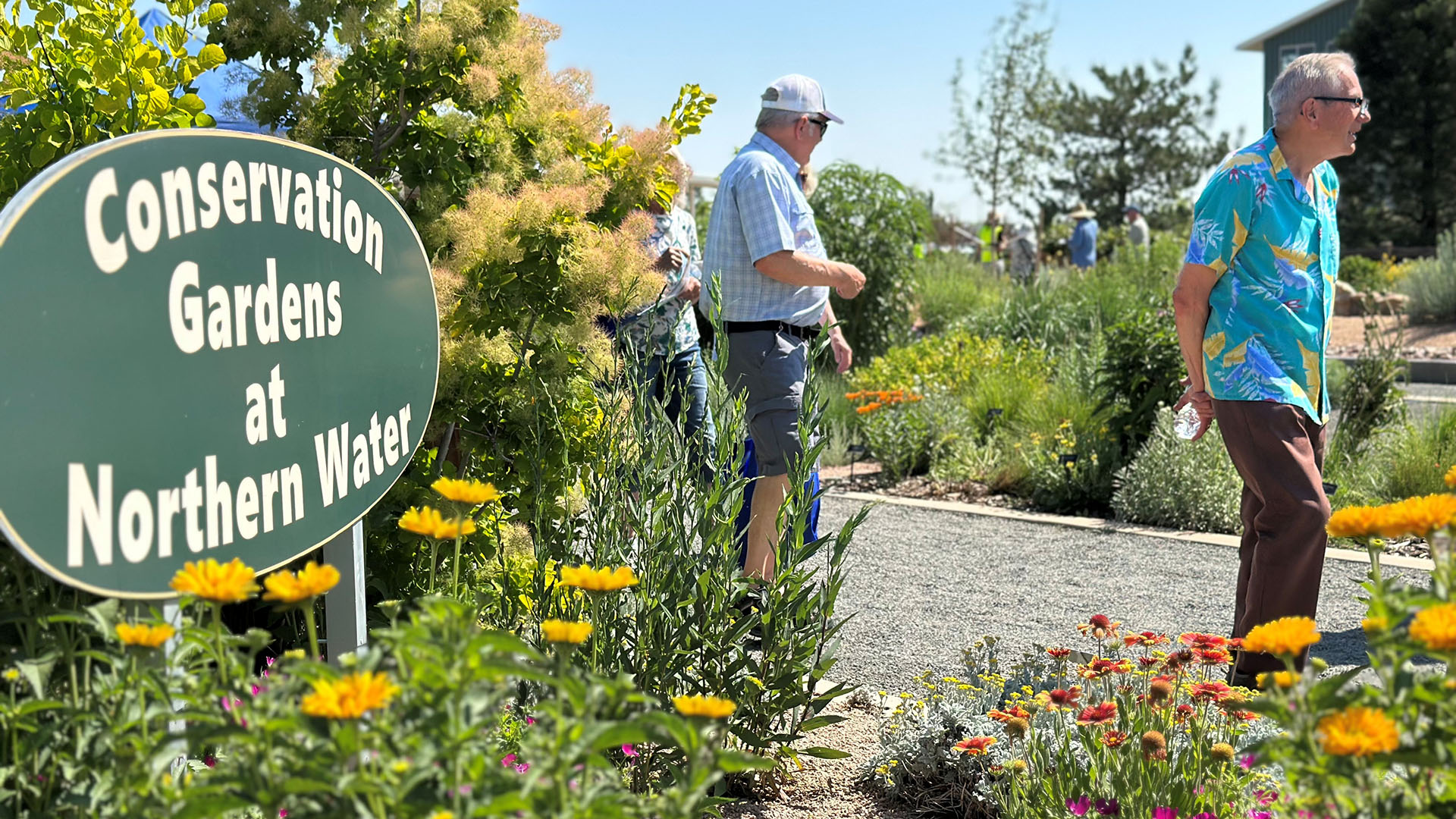 Two men walking near a sign for the Conservation Gardens. 
