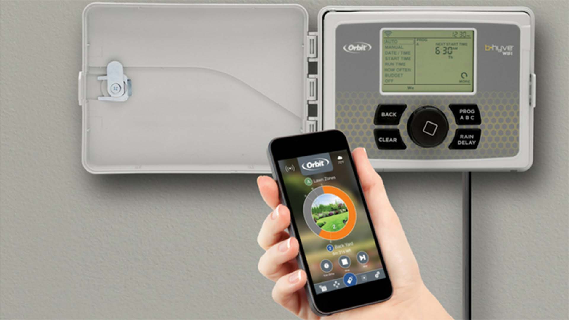 Human hand holding a cell phone in front of irrigation controller.