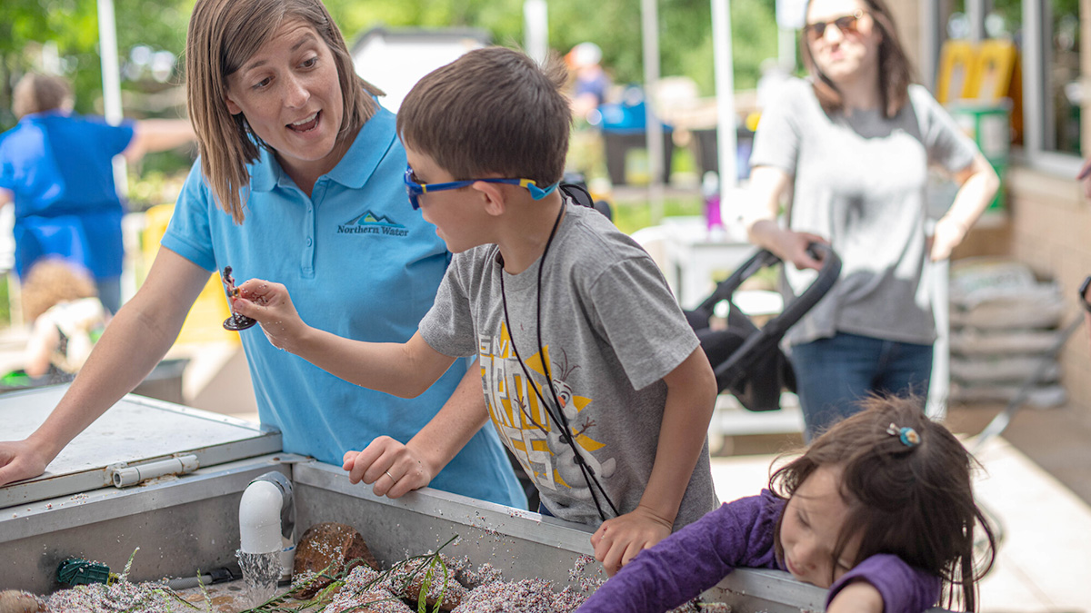 Kids at an activity table with an adult engaging with them.